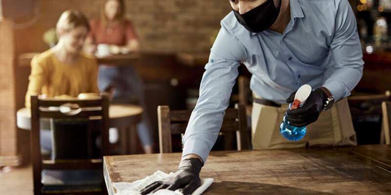 Food and beverage employee cleaning a table at a restaurant